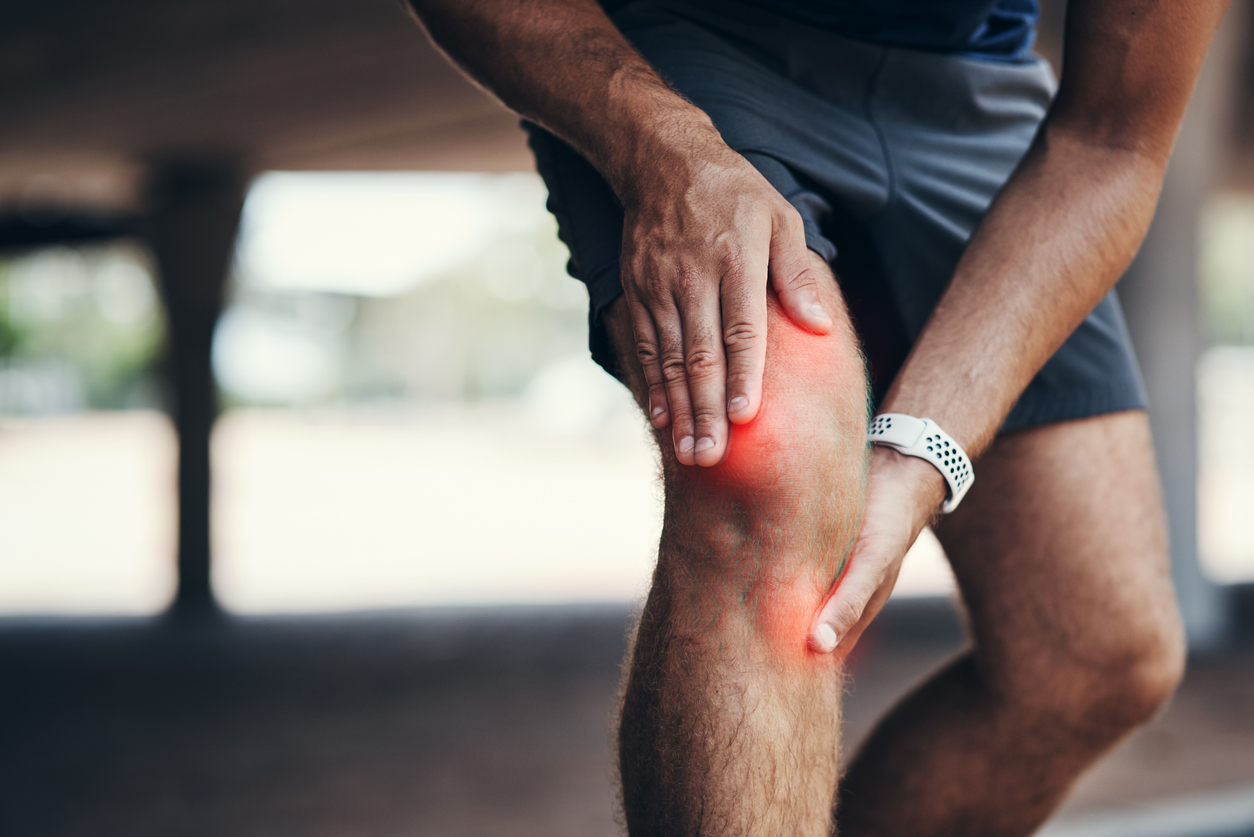 Closeup shot of an unrecognizable man holding his knee in pain while exercising outdoors