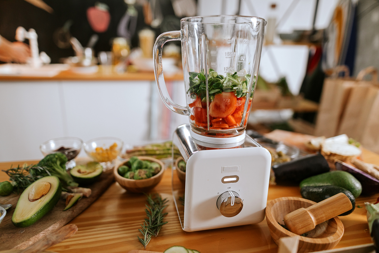 Healthy vegetarian ingredients in juice blender on domestic kitchen table