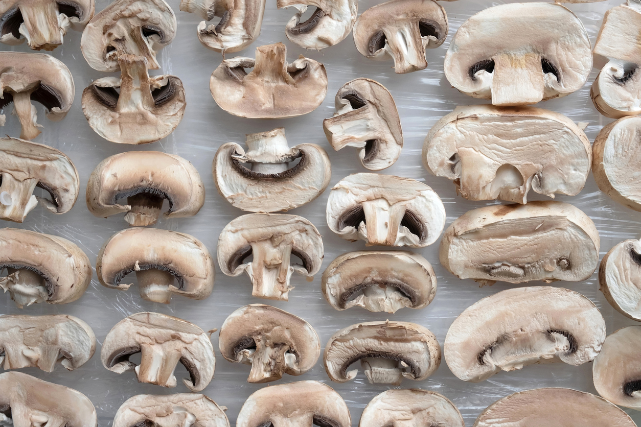 Sliced champignon mushrooms on the kitchen table.